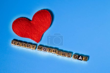 Foto de Una palabra hecha de letras. Feliz Día de la Madre. Corazón rojo. Fondo azul. Celebraciones. - Imagen libre de derechos