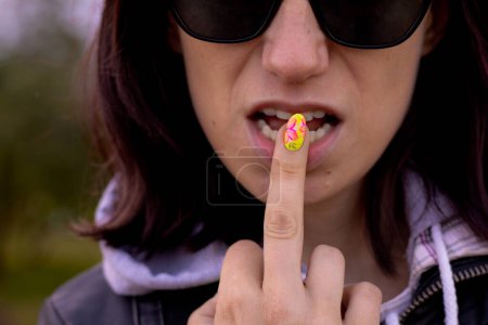 Photo for A woman's finger is put to her lips as a sign of not speaking. Soft selective focus. - Royalty Free Image