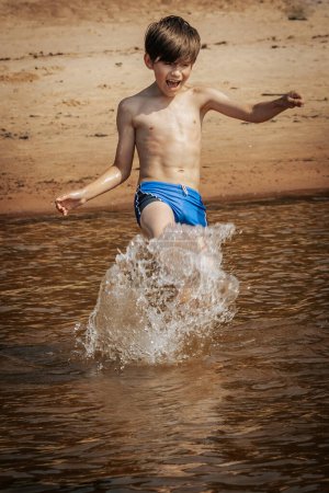 Photo for Boy running and splashing with water, summer vacation. Soft selective focus. - Royalty Free Image