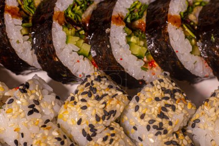 Foto de Conjuntos de sushi de diferentes sabores de hojas de nori, arroz, pepino, salmón. El sushi rueda sobre un fondo blanco. Enfoque selectivo mixto. - Imagen libre de derechos