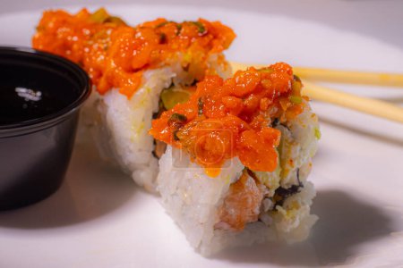 Foto de Hojas de Nori, arroz, pepino, conjuntos de sushi salmón de diferentes sabores. Rollos de sushi sobre un plato de fondo blanco con palillos. Enfoque selectivo mixto. - Imagen libre de derechos