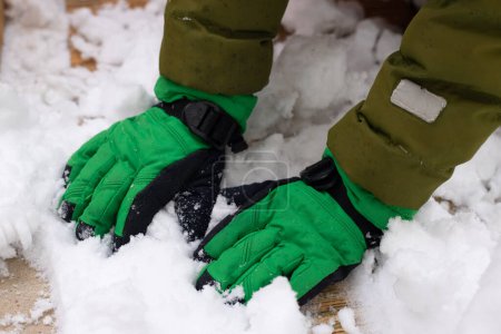 Téléchargez les photos : La neige recouvre le sol pendant l'hiver. Hiver avec neige glacée et gants garçon, sol enneigé et lumière du soleil. Concentration sélective douce. - en image libre de droit