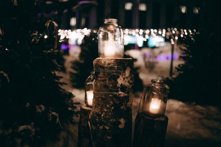 Photo for Bright architecture with festive lighting at night with a candle in a jar. The festive building is lit up with Christmas lights on a dark night. Atmospheric distortion, hot air distortion. - Royalty Free Image