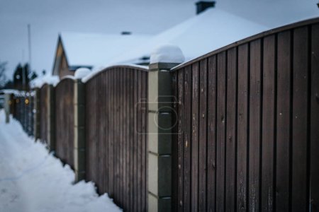 The fences of the city houses are covered with snow. And the roads are covered with snow. 