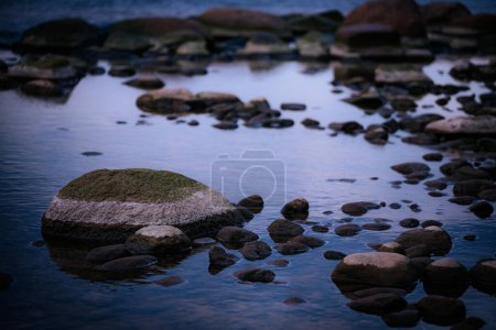 Stones on the seashore. Soft selective focus. Artificially created grain for the picture