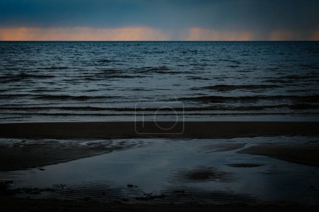 Pierres au bord de la mer avec coucher de soleil. Concentration sélective douce. Grains créés artificiellement pour l'image