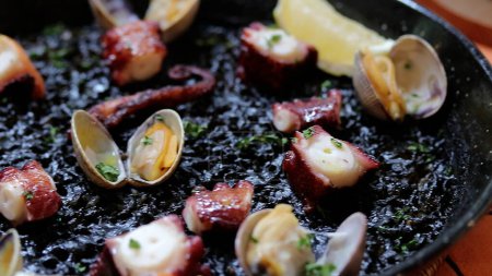 Téléchargez les photos : Paella Encre Noire à la Pieuvre et aux Palourdes, cuisine espagnole à Bangkok. - en image libre de droit