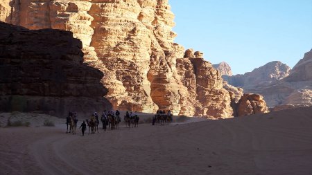 Foto de Turistas montando camellos en Wadi Rum Protected Área, Jordania. - Imagen libre de derechos