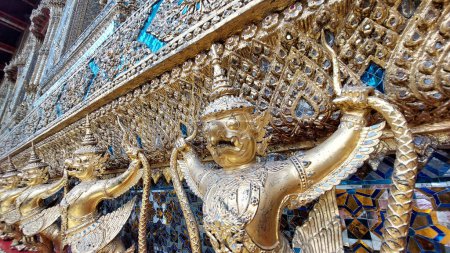 La fila dorada de Garudas en la base de Ubosot, Wat Phra Kaew, Tailandia.