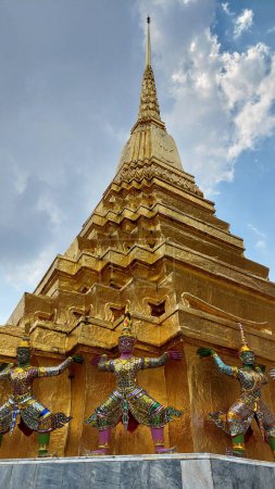Pagoda dorada con los gigantes de apoyo alrededor de la base, Wat Phra Kaew, Tailandia.
