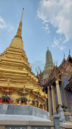 Pagoda dorada con los gigantes de apoyo alrededor de la base, Wat Phra Kaew, Tailandia.