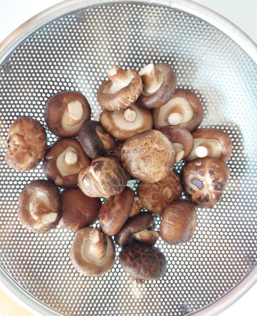 Champignons Shitake frais dans un panier en acier inoxydable.