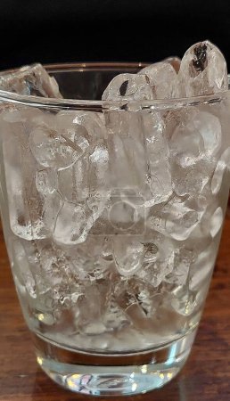 Ice Cube in Drinking Glass on Wooden Table, Restaurant in Bangkok.
