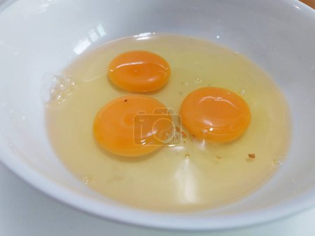 Prepare la comida agrietando huevos frescos en un tazón blanco.