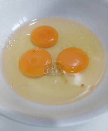 Bereiten Sie das Essen zu, indem Sie frische Eier in eine weiße Schüssel knacken.