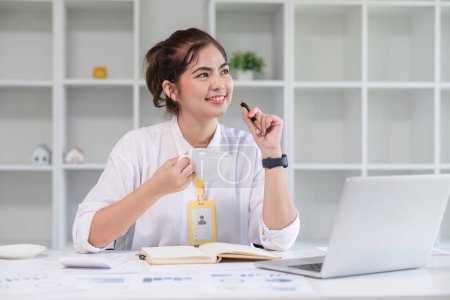 Foto de Hermosa joven emprendedora riendo usando el ordenador portátil y tomando café en su escritorio en la moderna oficina en casa. - Imagen libre de derechos