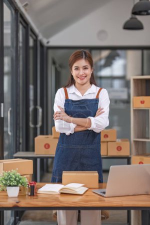 Foto de Startup small business entrepreneur SME, asian woman packing cloth in box. Portrait young Asian small business owner home office, online sell marketing delivery, SME e-commerce telemarketing concept. - Imagen libre de derechos