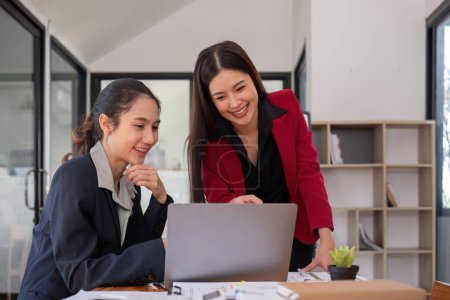 Photo for Two businesswomen discussing project strategy in office conference room Businesswoman discusses project planning with colleagues in modern workplace, gives advice on financial data report. - Royalty Free Image