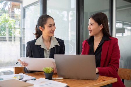 Photo for Two businesswomen discussing project strategy in office conference room Businesswoman discusses project planning with colleagues in modern workplace, gives advice on financial data report. - Royalty Free Image