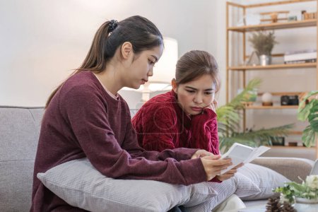 Two women focused on calculating finances with laptop at home. Concept of financial planning, collaboration, and budgeting.