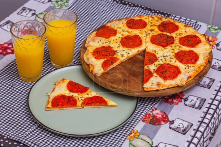 Foto de Deliciosa pizza de pepperoni en rodajas, pizza horneada, pizza casera con jugo de naranja - Imagen libre de derechos