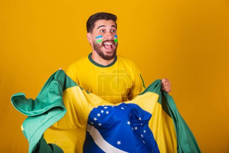 Photo for Brazilian man, latin american, cheering for brazil, in world cup 2022, Patriot, nationalist, Vibrating brazil flag, cheering, symbol of happiness, joy and celebration, with brazil flag - Royalty Free Image