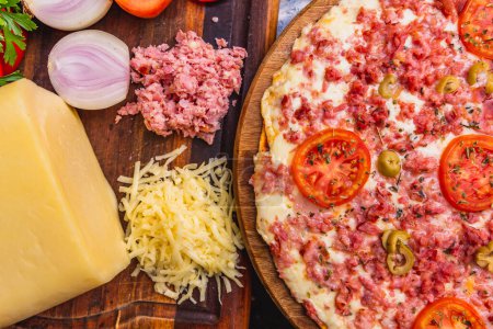 Photo for Delicious mixed cheese and ham pizza, ready, baked pizza, home pizza. next to wooden board with ingredients - Royalty Free Image