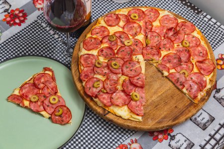 Foto de Deliciosa pizza de pepperoni sobre tabla de madera en la parte superior del mantel - Imagen libre de derechos