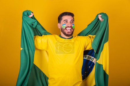 Photo for Brazilian man, latin american, cheering for brazil, in world cup 2022, Patriot, nationalist, Vibrating brazil flag, cheering and jumping, symbol of happiness, joy and celebration, with brazil flag - Royalty Free Image