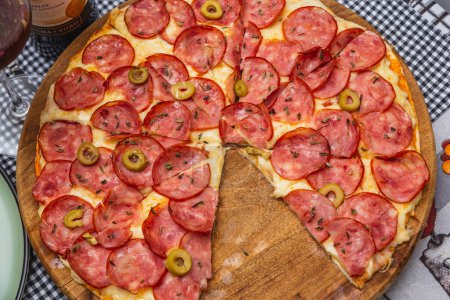Foto de Deliciosa pizza de pepperoni sobre tabla de madera en la parte superior del mantel - Imagen libre de derechos