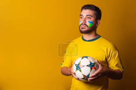 Foto de Hombre latinoamericano brasileño animando a Brasil en la Copa del Mundo 2022, sosteniendo la pelota de fútbol, en seriedad, jugador, compromiso, copa de fútbol, fútbol. ventilador - Imagen libre de derechos