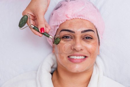 Téléchargez les photos : Massage facial sur la peau du patient, à l'aide d'un outil appelé pierre de jade, soin de la peau - en image libre de droit