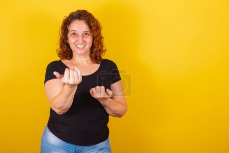 Kaukasische, brasilianische, lateinamerikanische Frau, lockiges Haar, Locken, gelber Hintergrund, mit Händen, die rufen: Komm, komm, willkommen, komm her.,