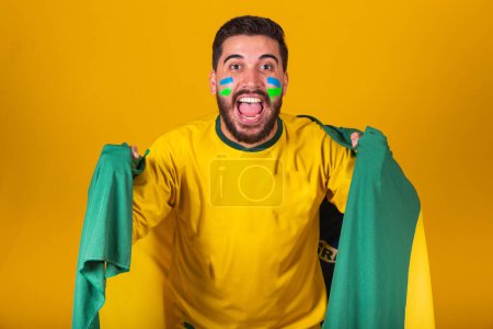 Photo for Brazilian man, latin american, cheering for brazil, in world cup 2022, Patriot, nationalist, Vibrating brazil flag, cheering and jumping, symbol of happiness, joy and celebration, with brazil flag - Royalty Free Image