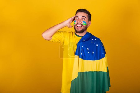 Foto de Hombre brasileño, latinoamericano, animando a Brasil, en la copa del mundo 2022, patriota, nacionalista, ansioso, atento, mirando al campo, sorprendido, expresión de atención y suspenso, feliz - Imagen libre de derechos