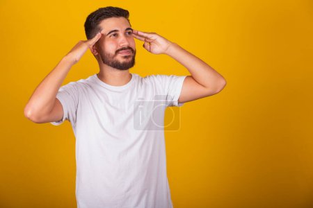 Photo for Brazilian Latin American man with hands on forehead and chin representing thought, pensive, doubt, questioning, decision, uncertainty, yellow background - Royalty Free Image