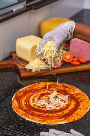 Photo for Pizza preparation, spreading mozzarella cheese on pizza dough, Fresh pizza ingredients on wooden board. - Royalty Free Image