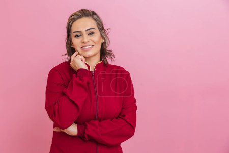 Photo for Brazilian woman, entrepreneur, aesthetic professional, with a red coat. with hand on chin, smiling, confident, cheerful and optimistic. - Royalty Free Image
