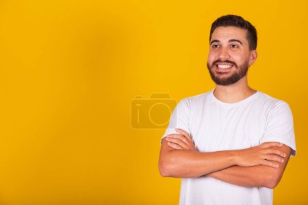Photo for Latin American man with arms crossed, smiling, empowered, confident, happy, yellow background, copy space - Royalty Free Image