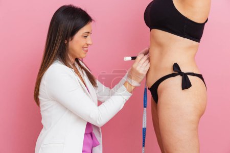 Photo for Aesthetics professional, performing measurements on the patient's abdomen, to perform an aesthetic procedure. - Royalty Free Image