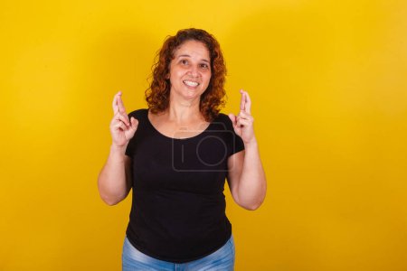 Photo for Caucasian, Brazilian, Latin American woman, curly hair, curls, yellow background, sign of luck, luck, draw, fingers crossed, lottery, wishing, cheering. - Royalty Free Image