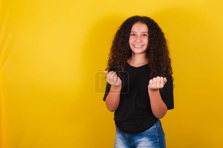 Foto de Brasileña, chica latinoamericana, para, pelo afro, fondo amarillo, sonriente, indicando ven, bienvenida, ven, con las manos y los dedos, ven aquí expresión - Imagen libre de derechos