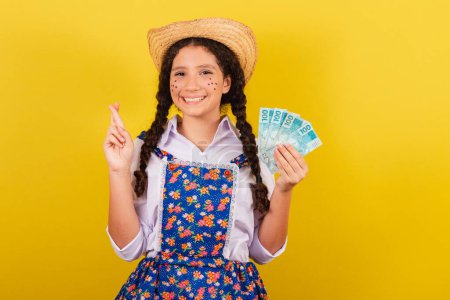 Photo for Girl wearing typical clothes for Festa Junina. Fingers crossed, luck wishing and hoping. For the Arraia party - Royalty Free Image
