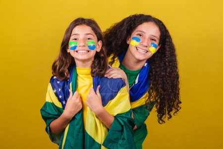 Photo for Sisters and friends supporters of Brazil, football fans, smiling at the camera watching the Brazil game. World Cup. Olympics. - Royalty Free Image