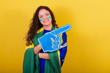 Foto de Mujer fanática del fútbol, fan de Brasil, copa del mundo, con guante de espuma. brazos cruzados, sonrientes, confiados. - Imagen libre de derechos