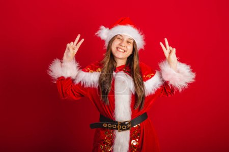 Téléchargez les photos : Caucasienne, Brésilienne en vêtements de Noël, Père Noël. position de paix et d'amour, pose selfie. - en image libre de droit