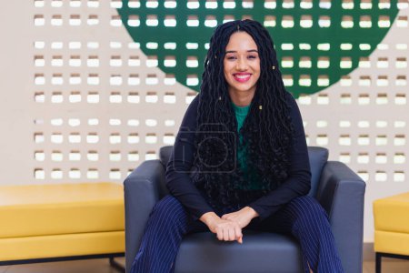 Photo for Young black woman, brazilian, entrepreneur, business woman, smiling optimist. Sitting in an armchair. - Royalty Free Image