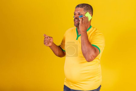 Téléchargez les photos : Homme noir brésilien, fan de football brésilien. bavarder par téléphone portable, appel vocal, smartphone. - en image libre de droit