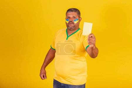 Photo for Brazilian black man, soccer fan from Brazil. showing yellow card. lack - Royalty Free Image