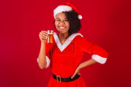 Photo for Beautiful black brazilian woman, dressed as santa claus, mama claus, drinking beer - Royalty Free Image
